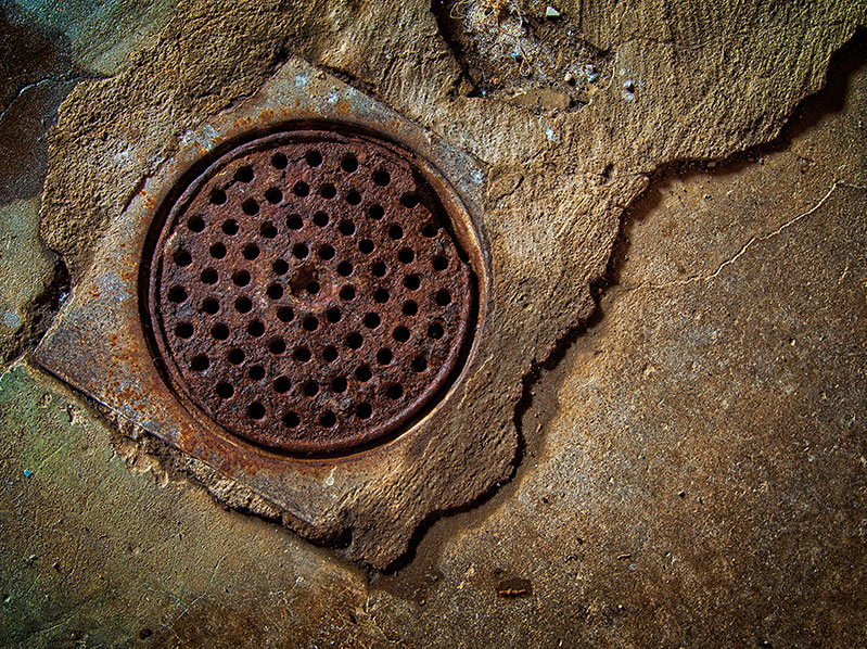 Rusted floor drain in a basement after flooding.